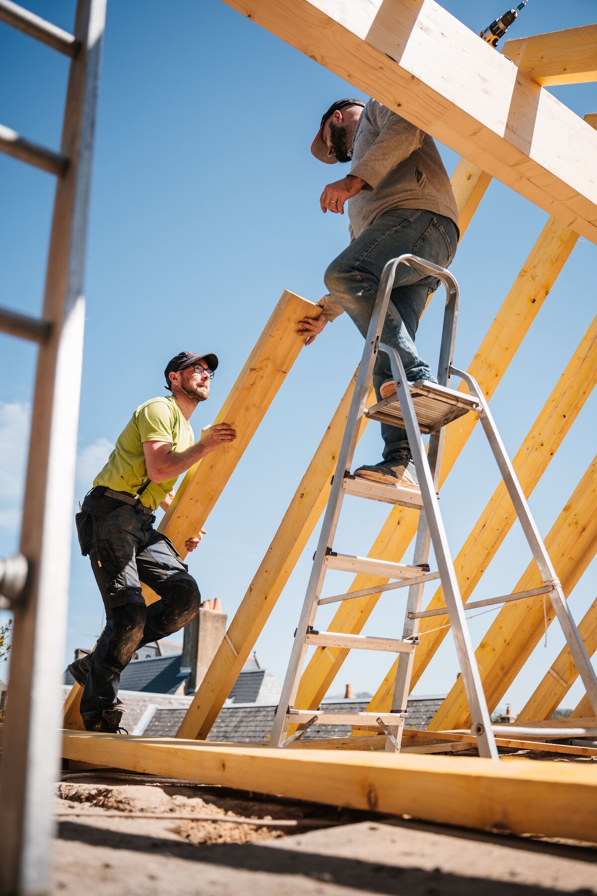 Builders framing roof rafters against a blue sky