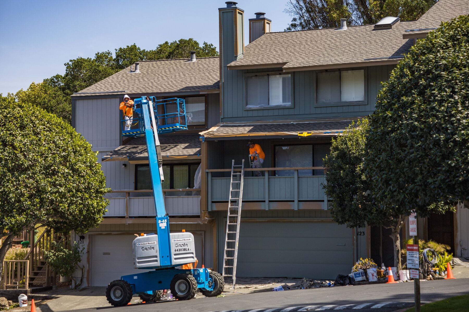 Crew working a multi-unit exterior from a boom lift and ladder